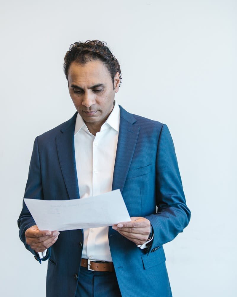 Photo by RDNE Stock project Confident businessman analyzing important documents in an office setting.